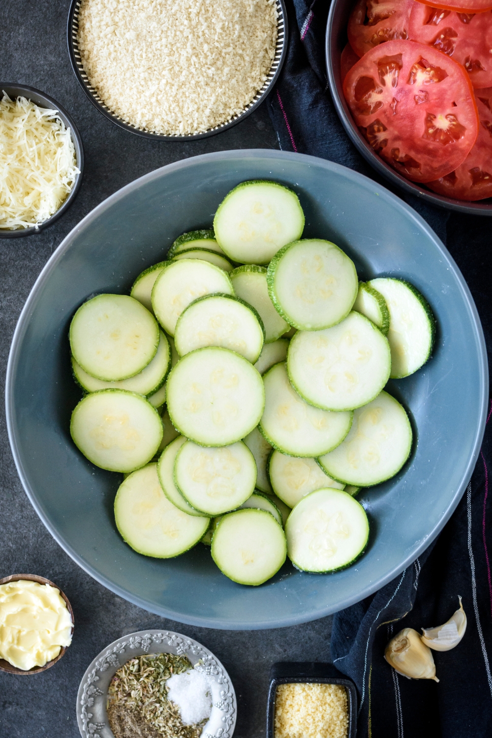 A mixing bowl with sliced zucchini and salt.