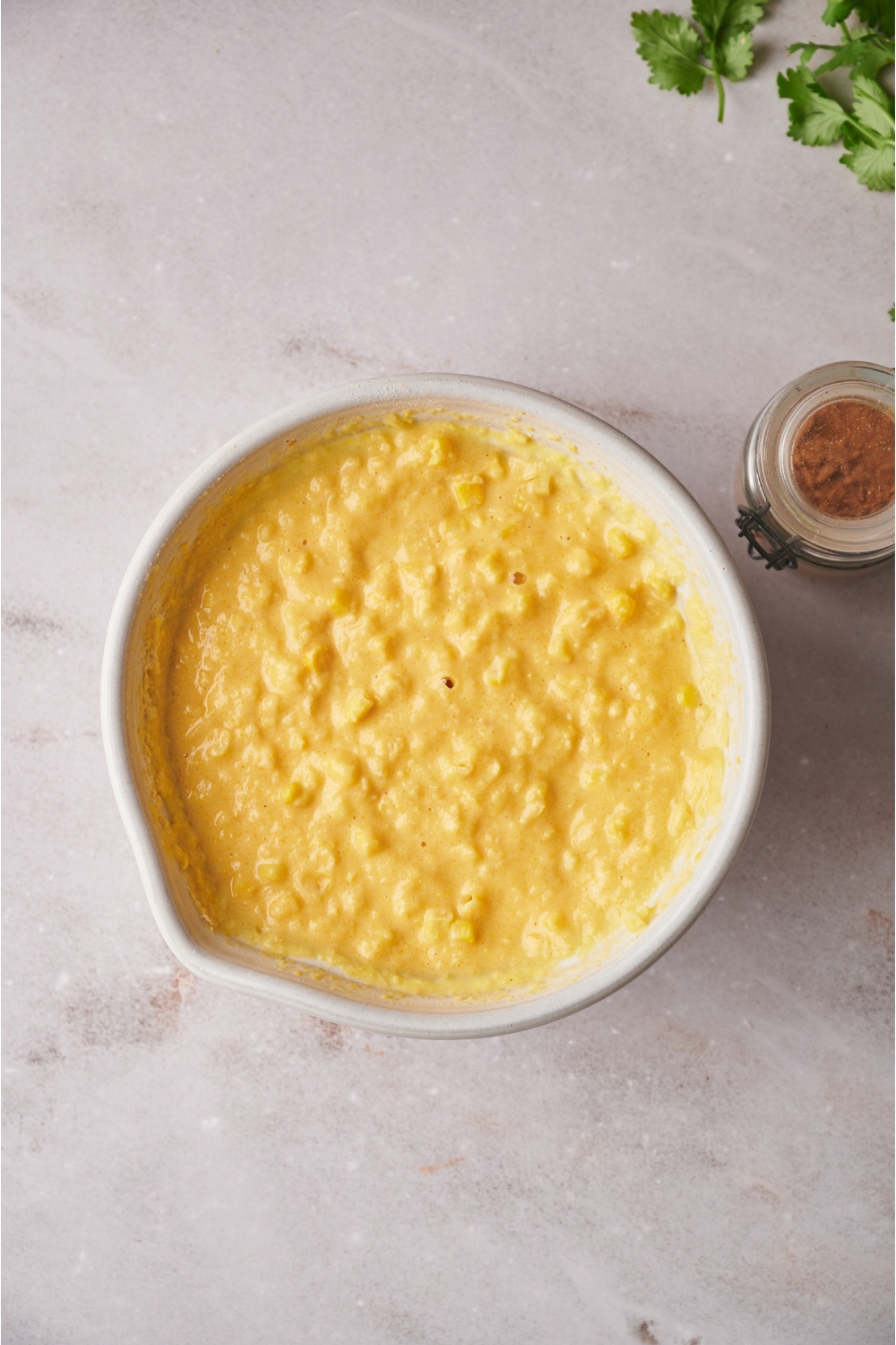 Cornbread batter in a white bowl on a grey counter.