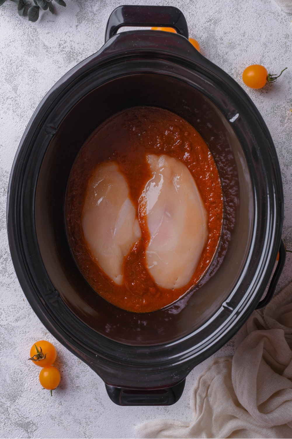 A crock pot with chicken and enchilada sauce.