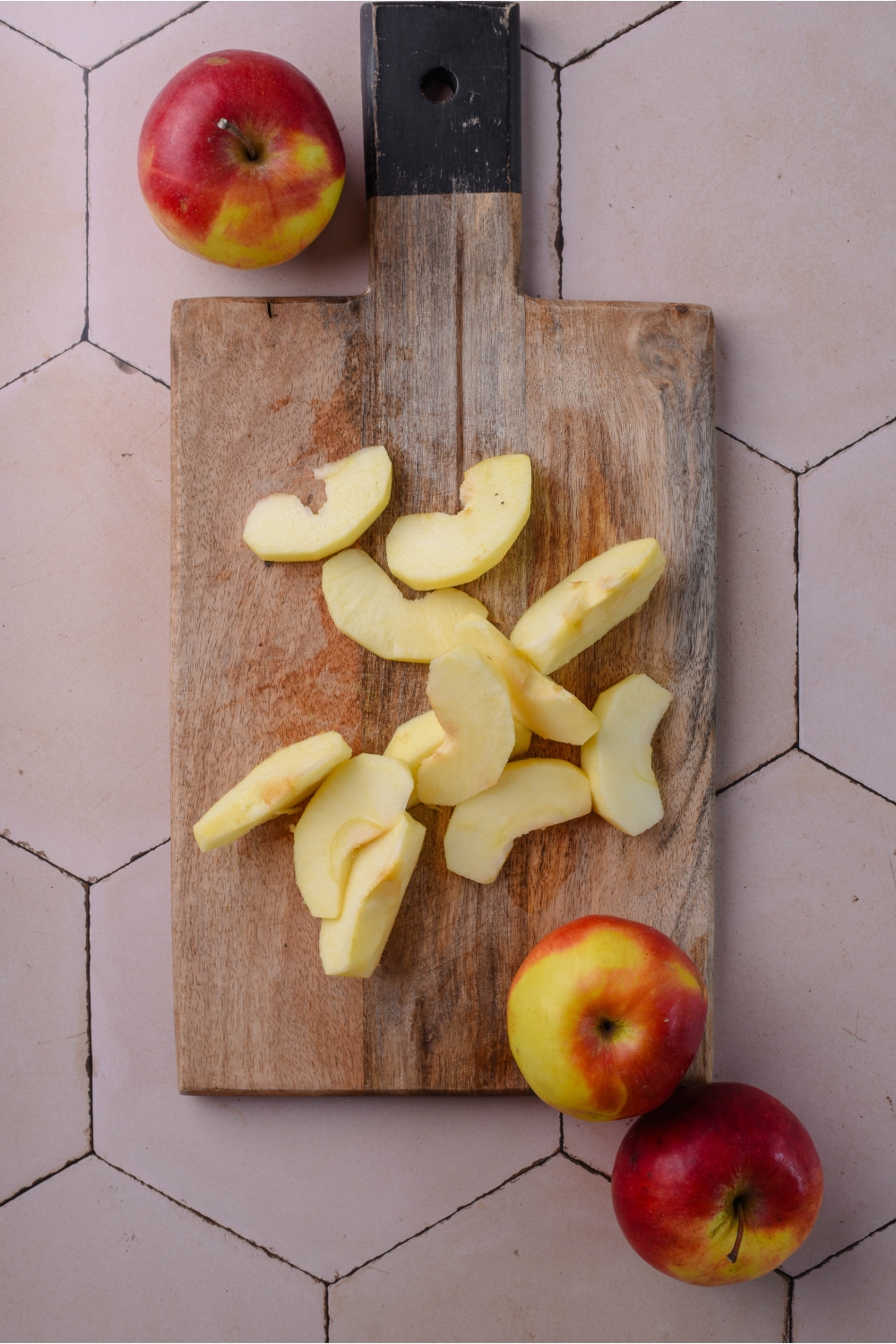 A wooden cutting board with sliced apples.