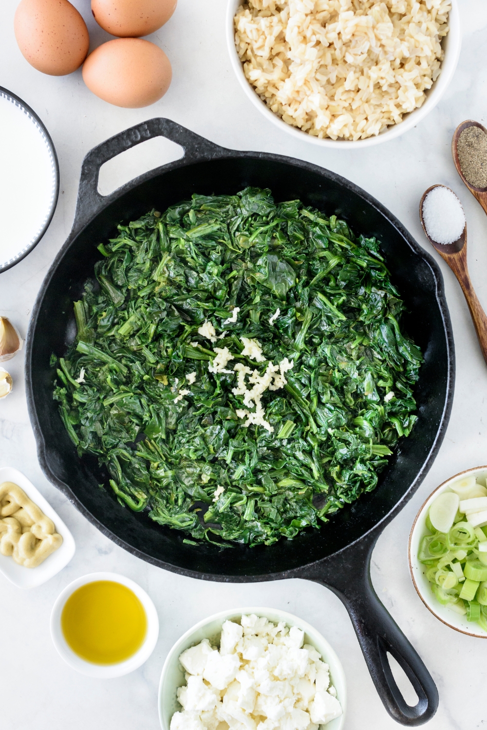 A skillet cooking the spinach and garlic.