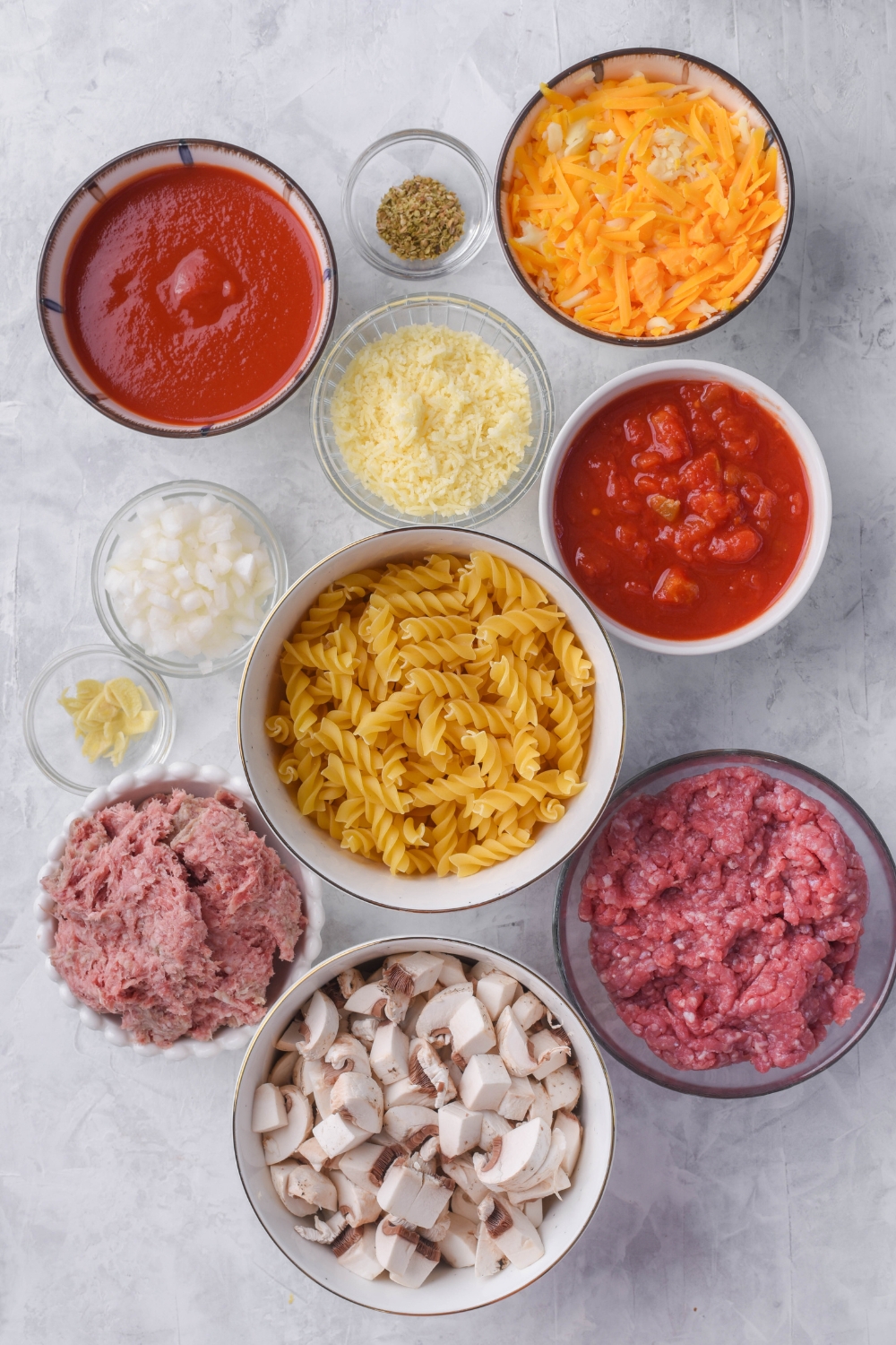 A countertop with multiple bowls containing ingredients to make johnny marzetti casserole.