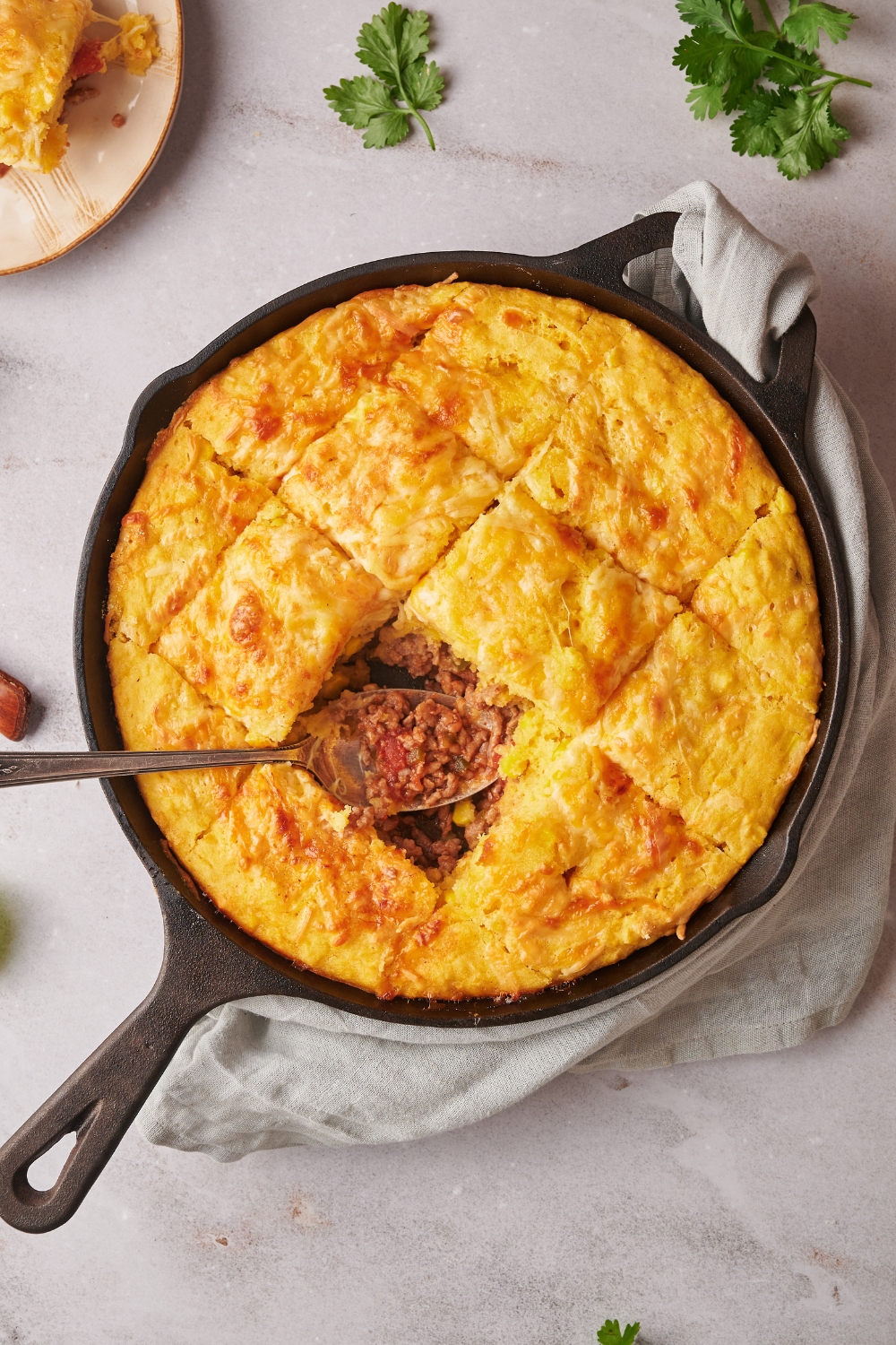 Mexican cornbread casserole cut into slices with one slice missing in a cast iron skillet.