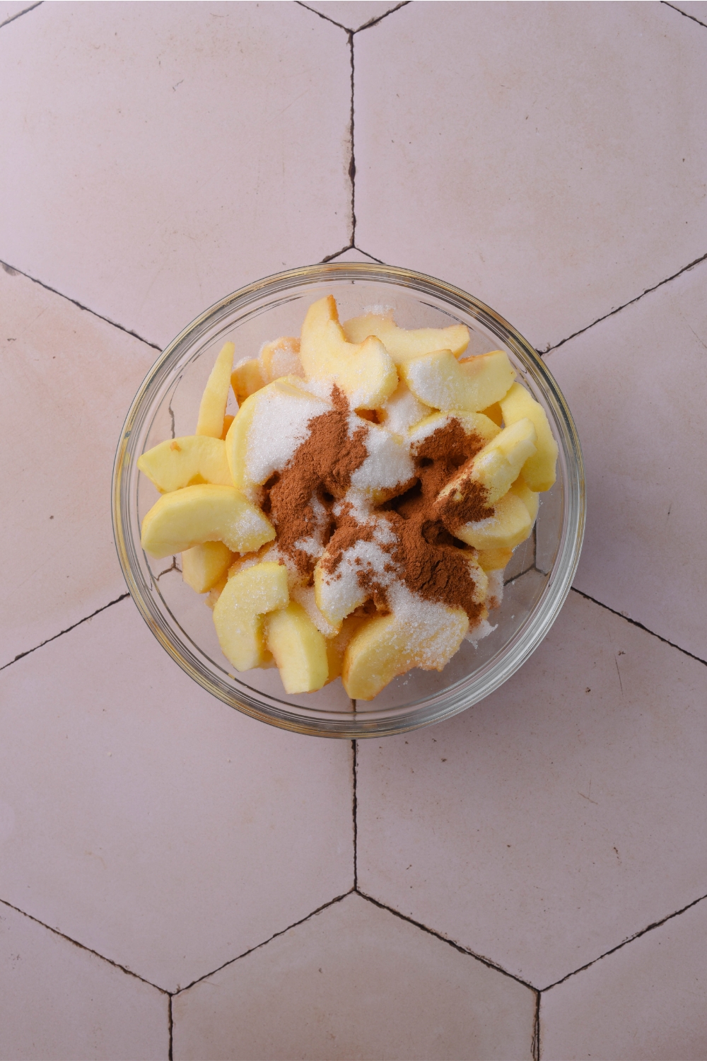 A mixing bowl with apples and dry ingredients.