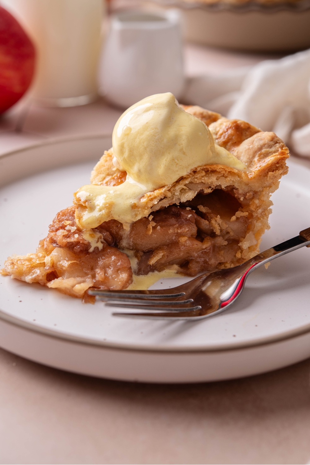 A plate with a slice of apple pie topped with a scoop of vanilla ice cream.