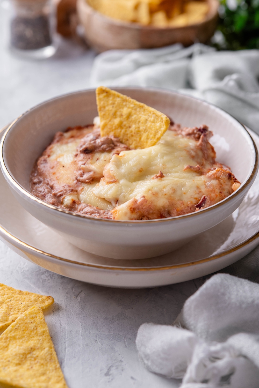 A bowl with bean dip and a tortilla chip dipped into it.