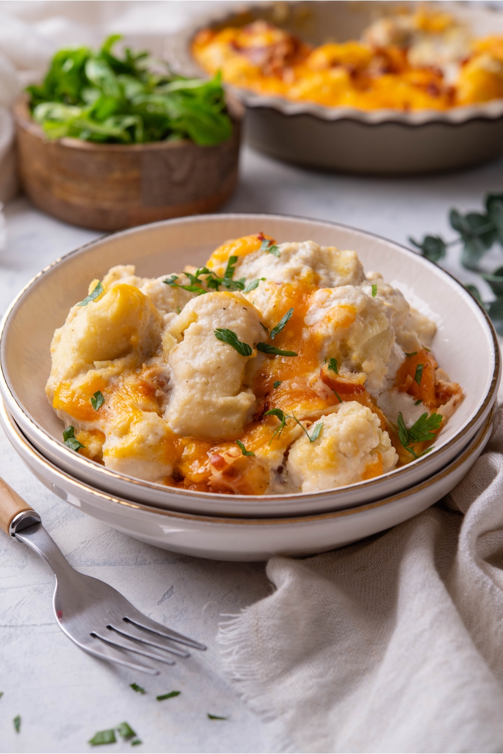 A bowl with cheesy tater tot casserole garnished with green onion.