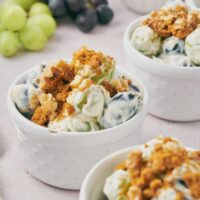 A few small bowls with grape salad topped with chopped nuts and crumbled spiced cookies.