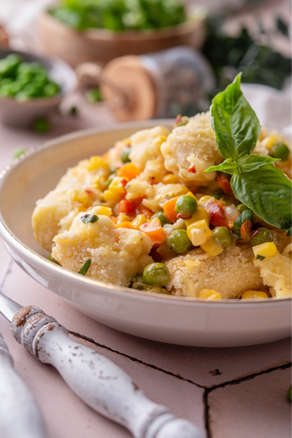 A bowl with vegetarian tater tot casserole garnished with a basil leaf.