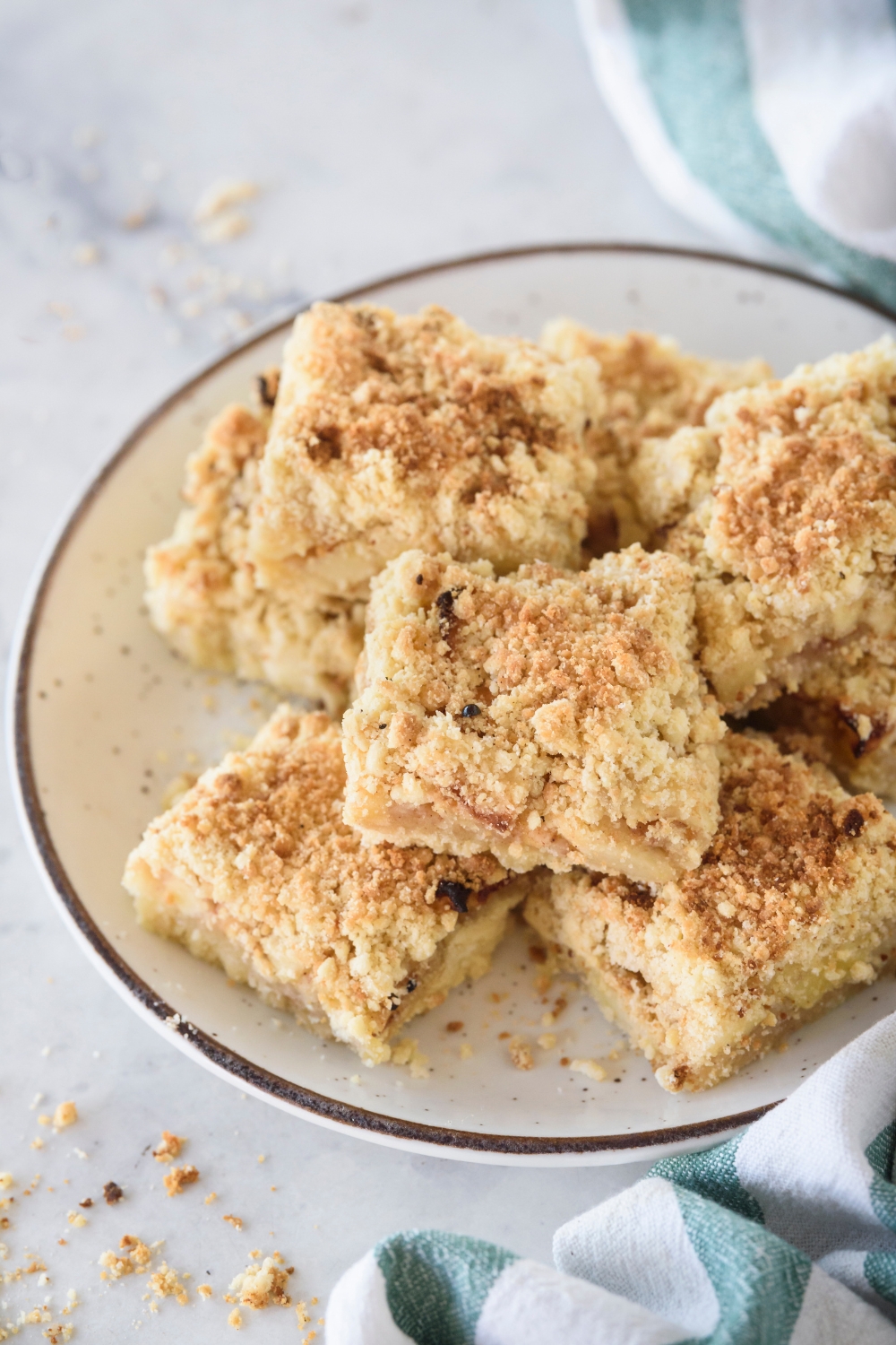 Apple pie bars piled high on a plate topped with a crumbly golden brown topping.