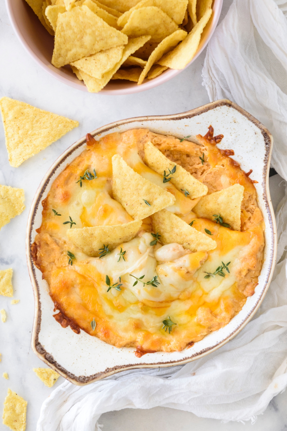 A baking dish filled with Buffalo chicken dip covered in melted cheese with tortilla chips sticking out of the dip.