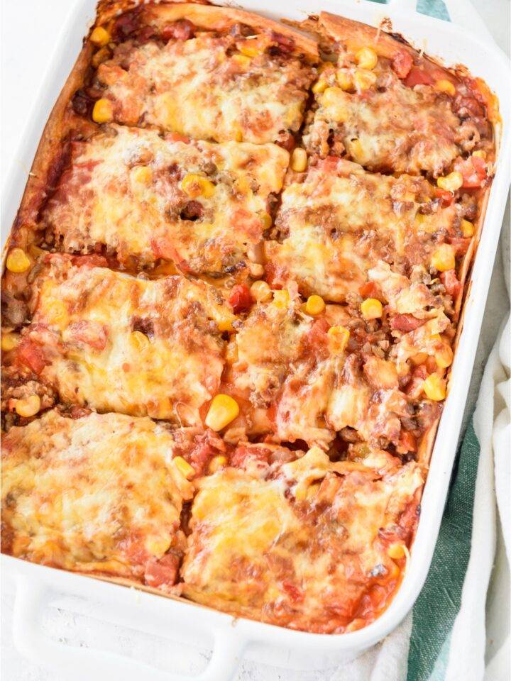A baking dish filled with freshly baked casserole covered in melted cheese and cut into eight equal-sized pieces.