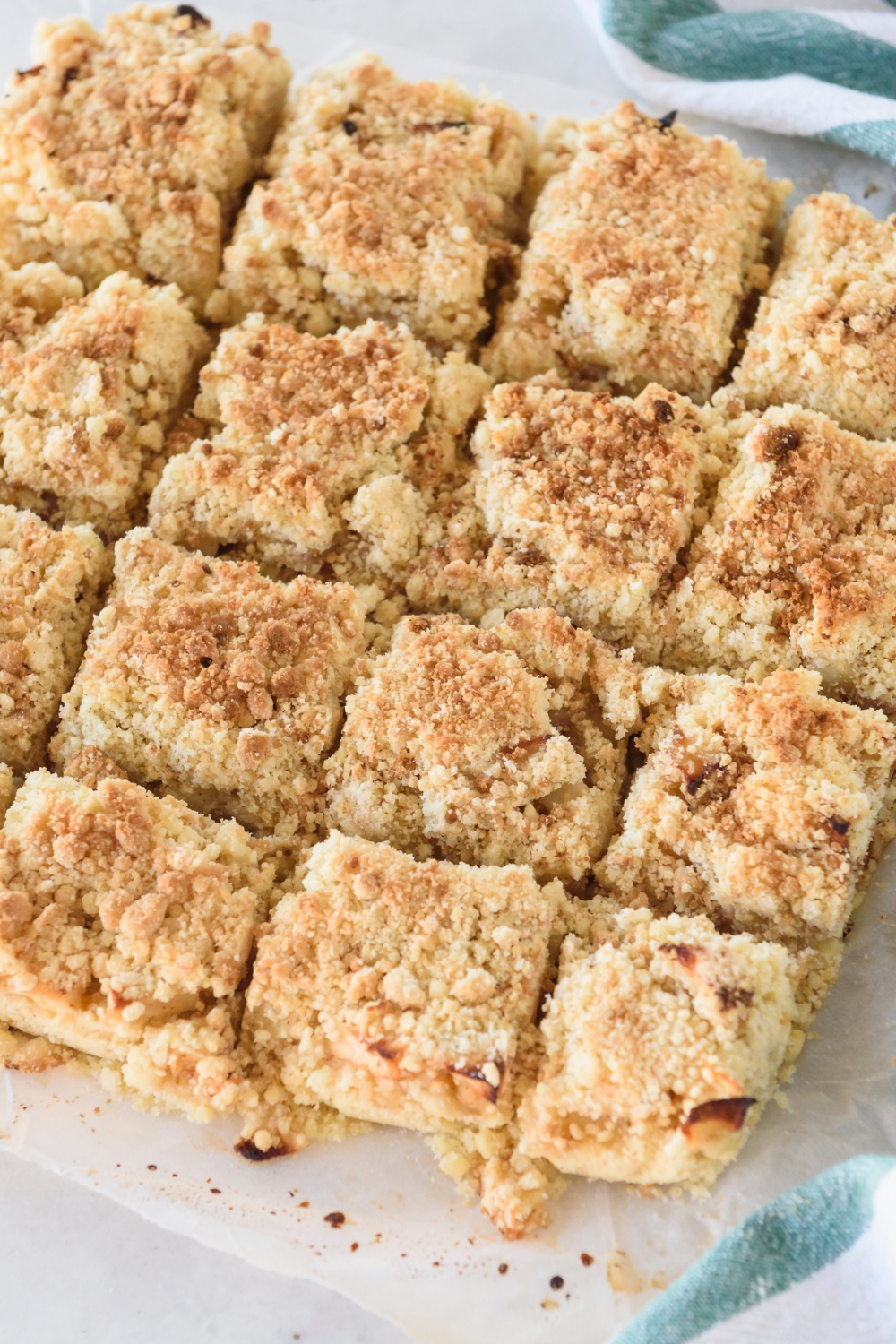 Apple pie bars cut into squares on a sheet of parchment paper.