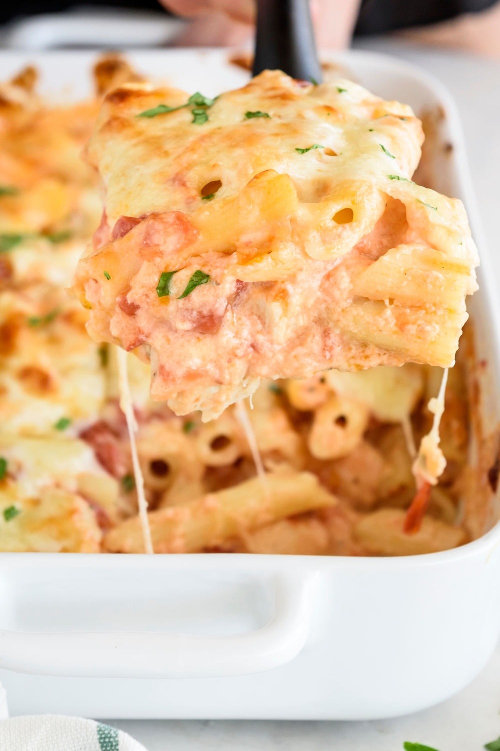 Close up of a scoop of baked pasta coated in a creamy tomato sauce with melted cheese.