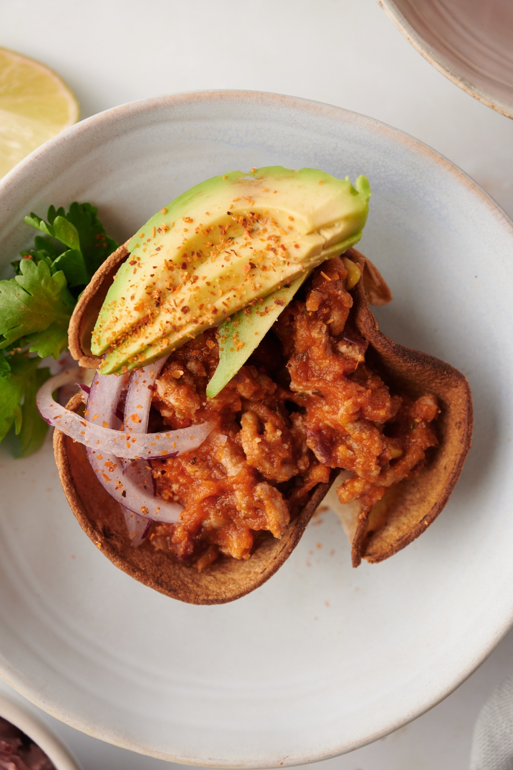 Mexican chili served with avocado and onion on a white plate