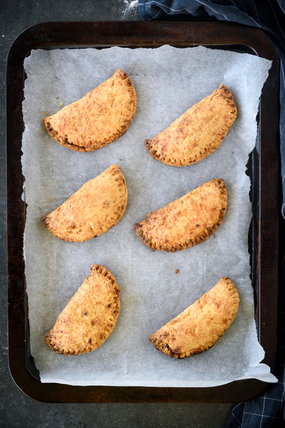 A baking sheet lined with parchment paper with six freshly baked hand pies.