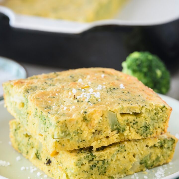 Two squares of broccoli cornbread stacked on top of each other garnished with sea salt.