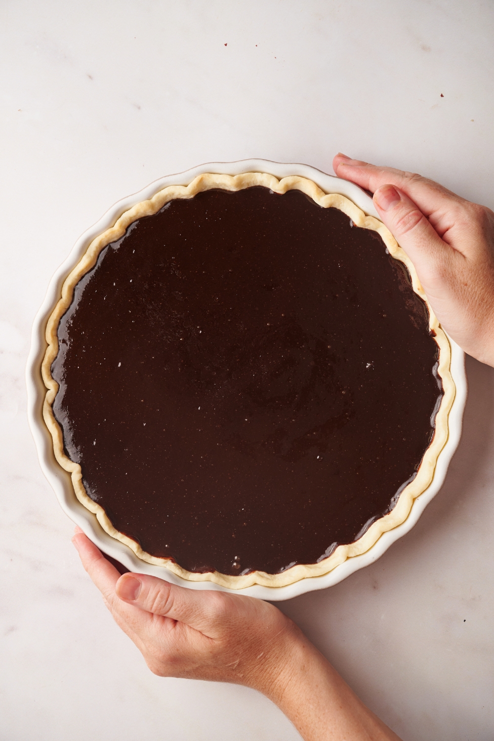two hands holding a chocolate pie in a pie pan