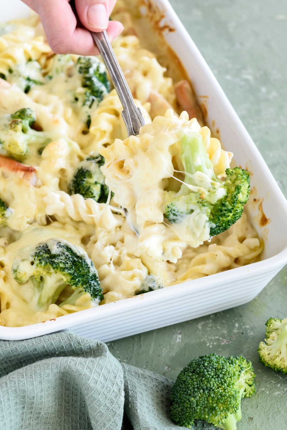 A spoonful of pasta covered in cream sauce with a broccoli floret.