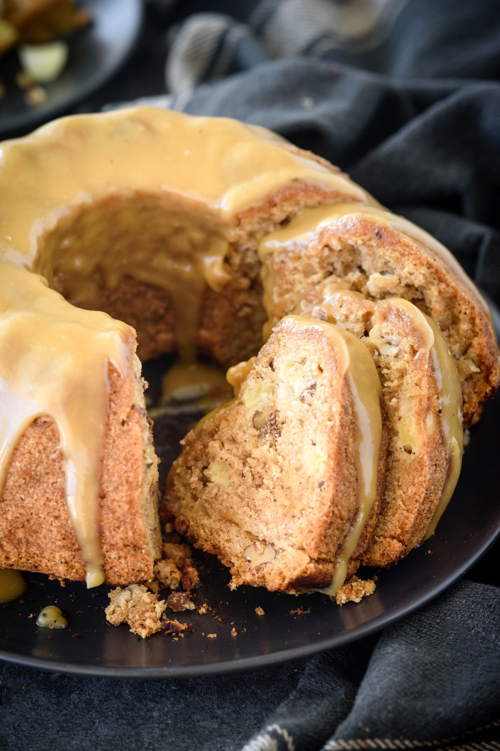 Bundt cake covered in caramel glaze and several slices have been cut from the cake and are resting against the cake.