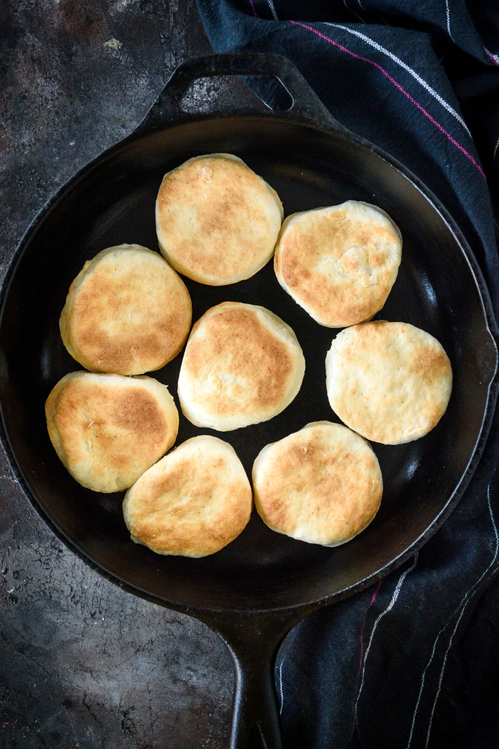 A cast iron skillet with eight biscuits in it.