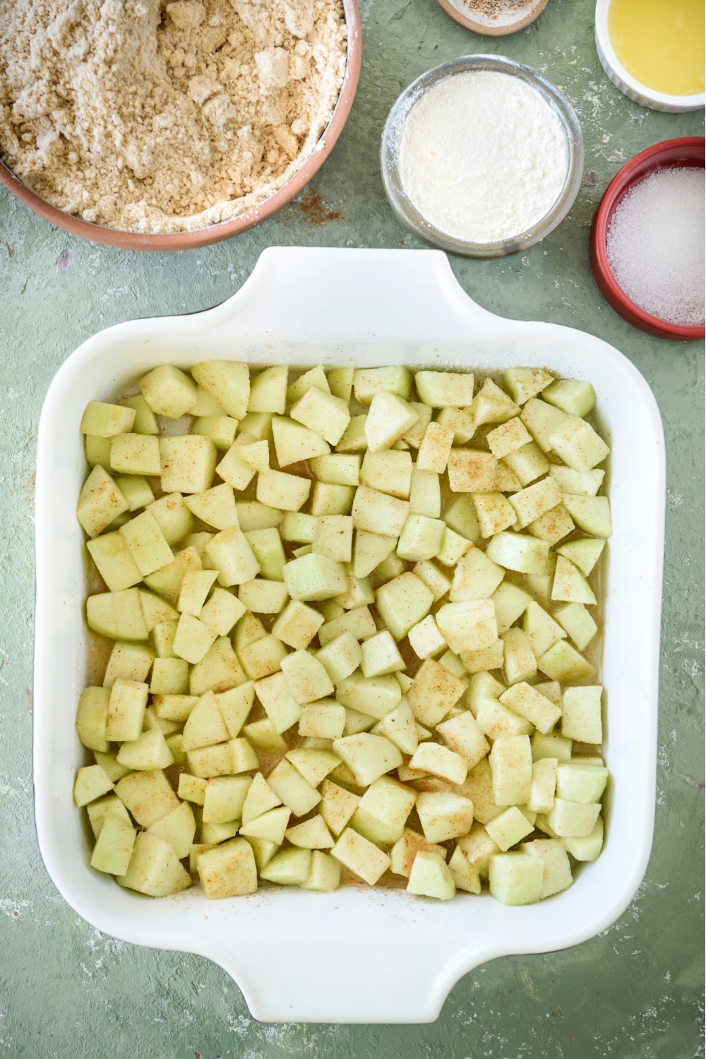 A baking dish filled with diced apples covered in spices.