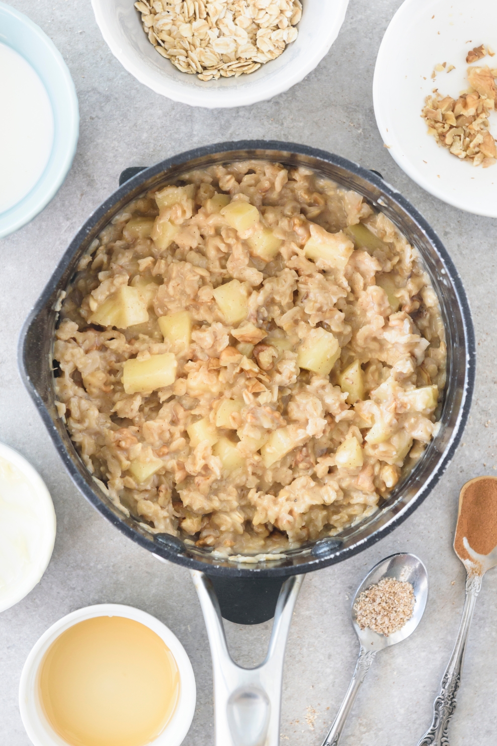 A pot filled with creamy oatmeal with diced apples and nuts mixed in.
