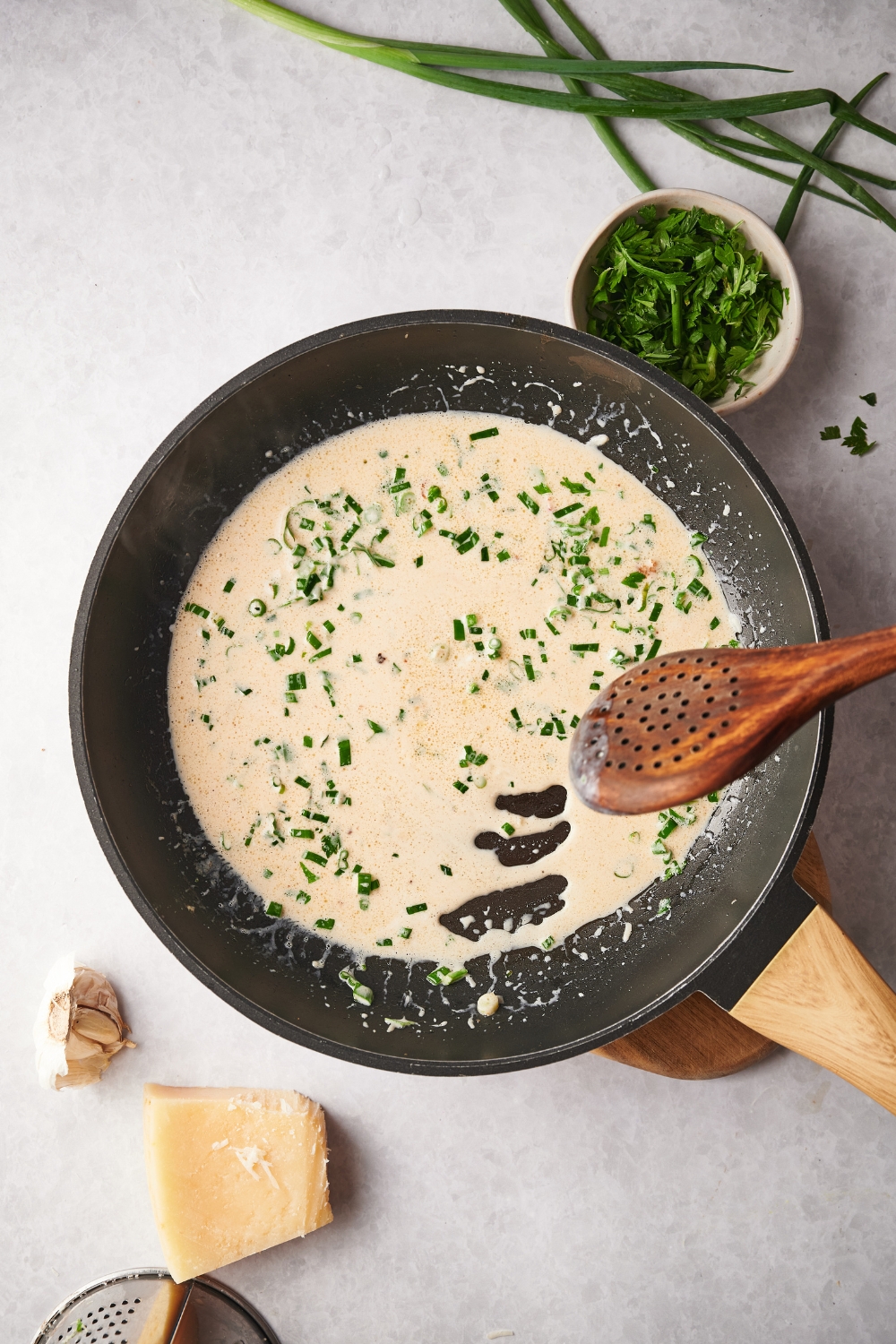 A skillet with herbs cooking in a cream sauce.