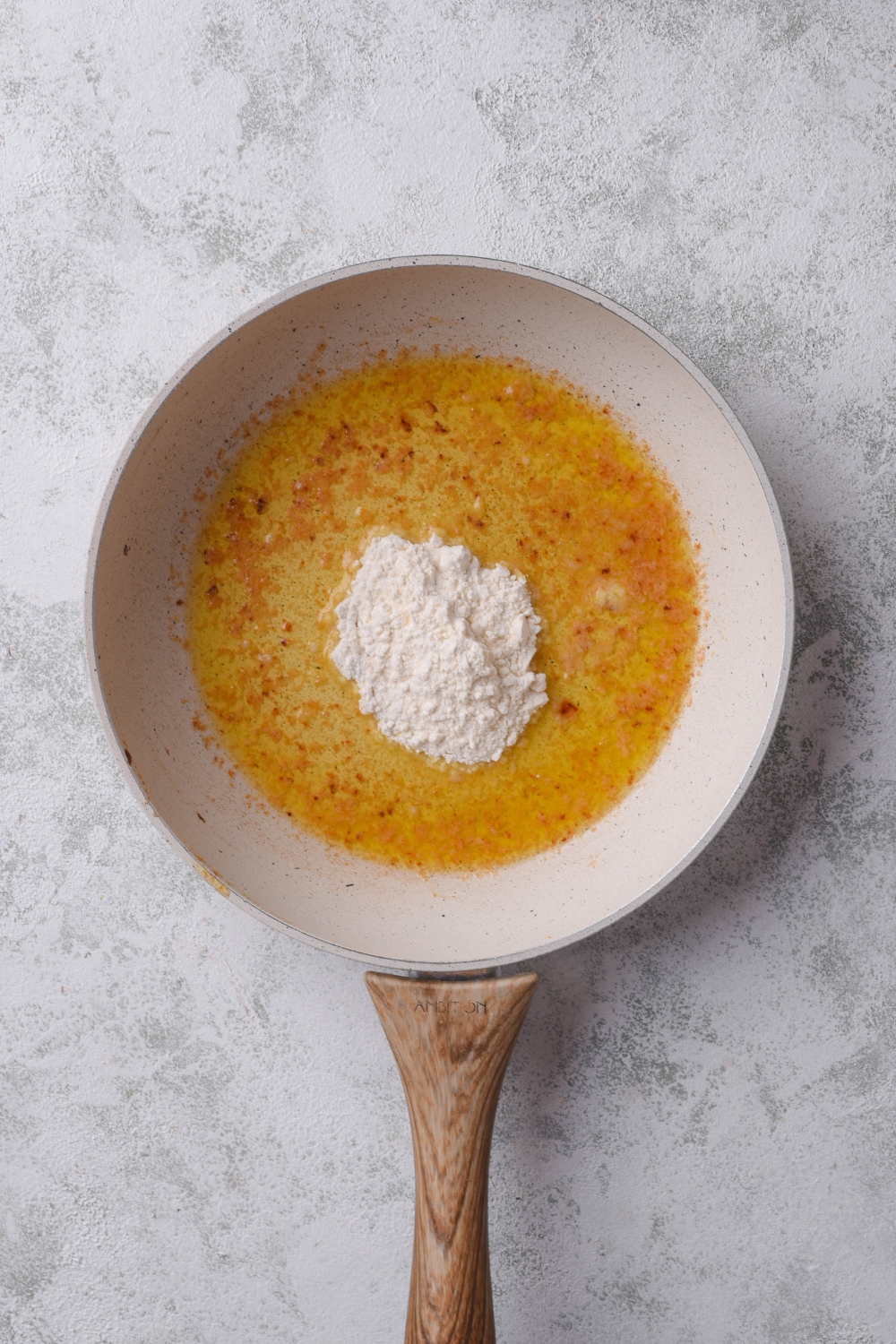 A skillet with seasoned melted butter and a pile of flour is in the center of the skillet.