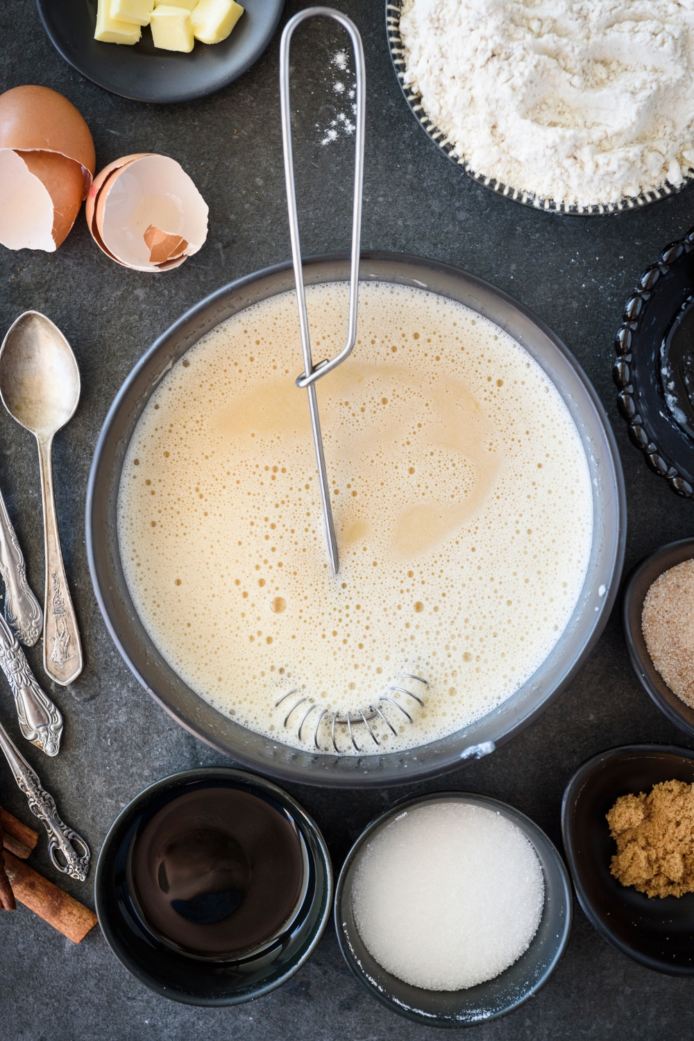 A bowl with a liquid mixture and an egg beater in the bowl.