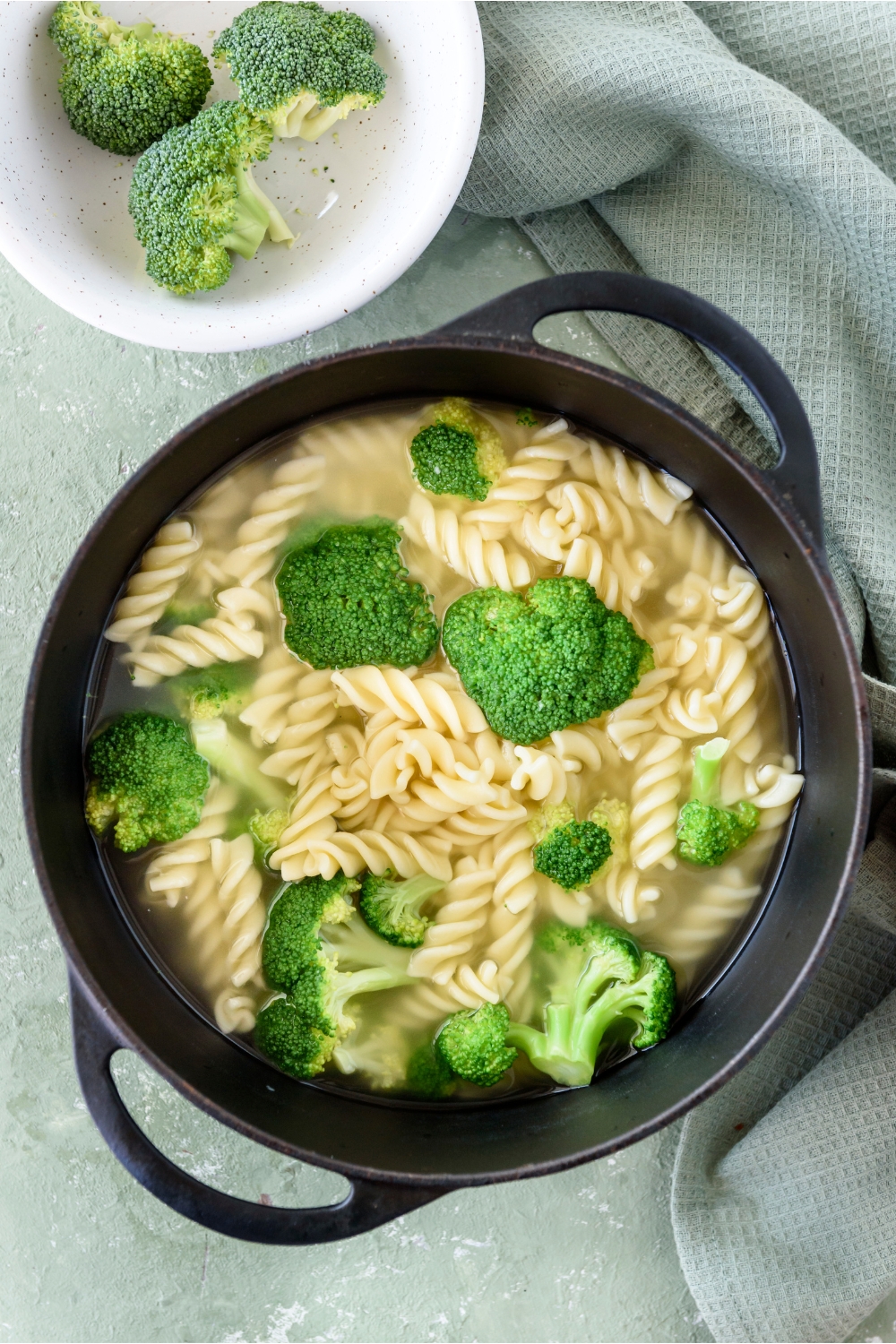 A pot filled with cooked pasta and broccoli florets in water.