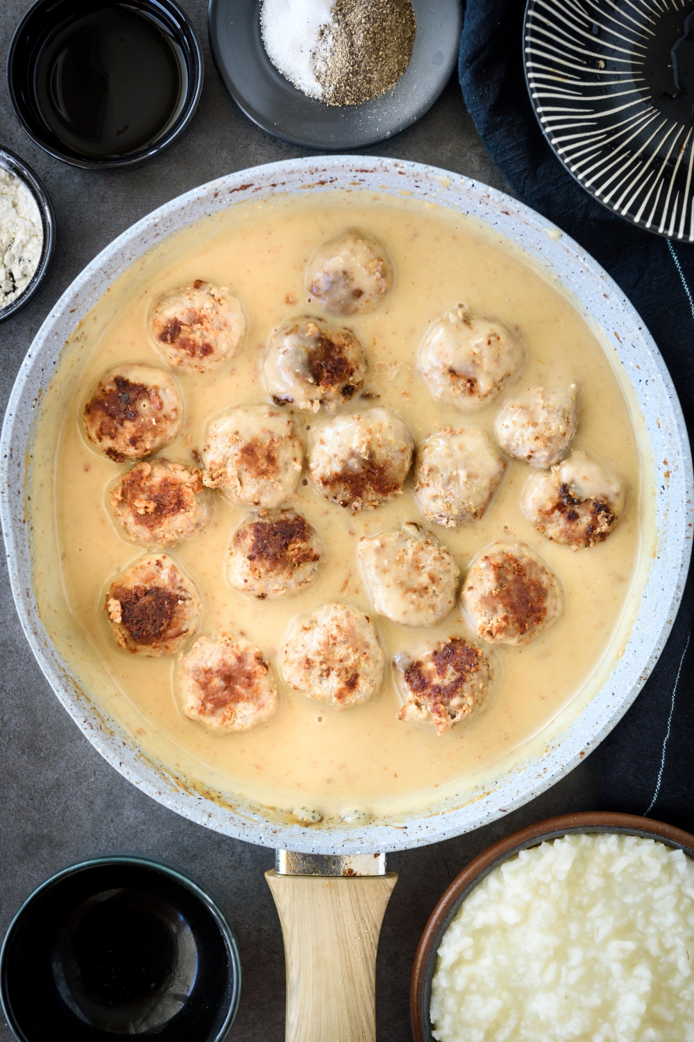A skillet filled with browned meatballs in a creamy sauce.