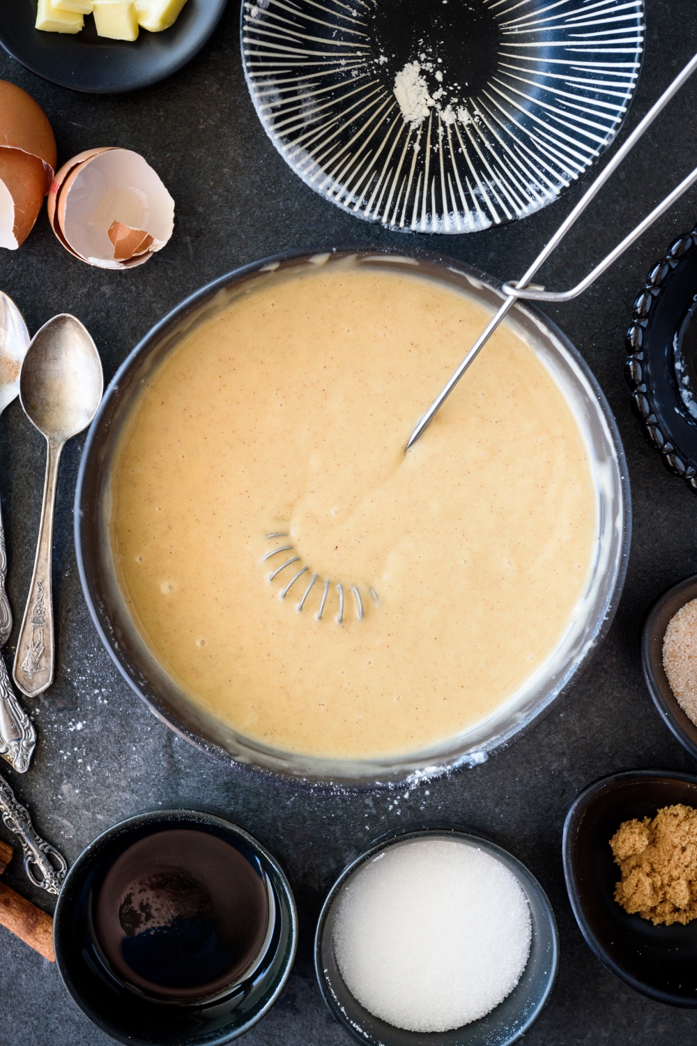 A bowl of batter with an egg beater in it.