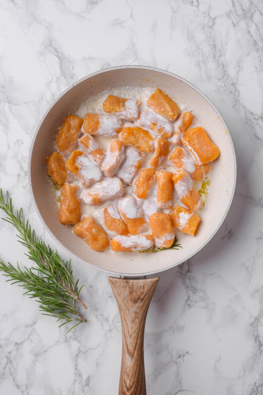 A skillet filled with sweet potato gnocchi and cream sauce.