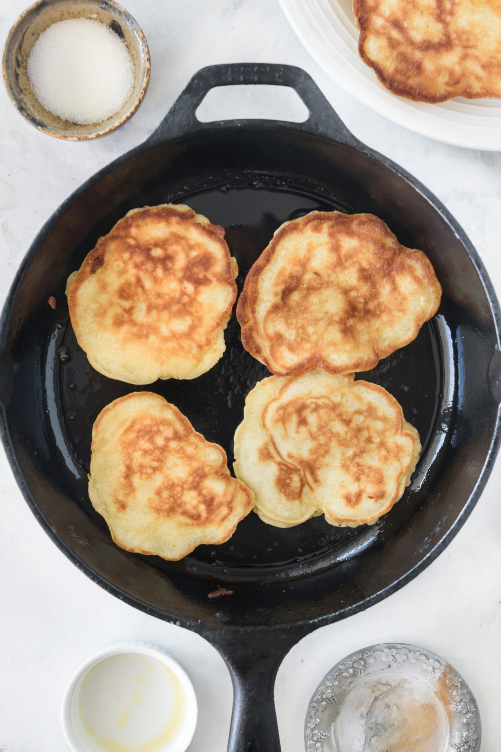 A cast iron skillet with four pancakes cooking in it.