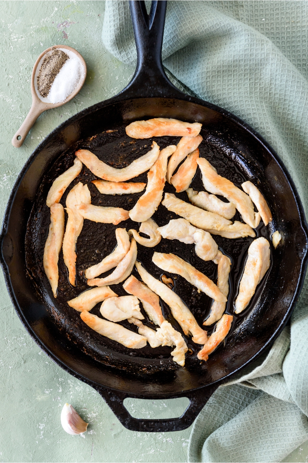 A cast iron skillet filled with cooked chicken strips.