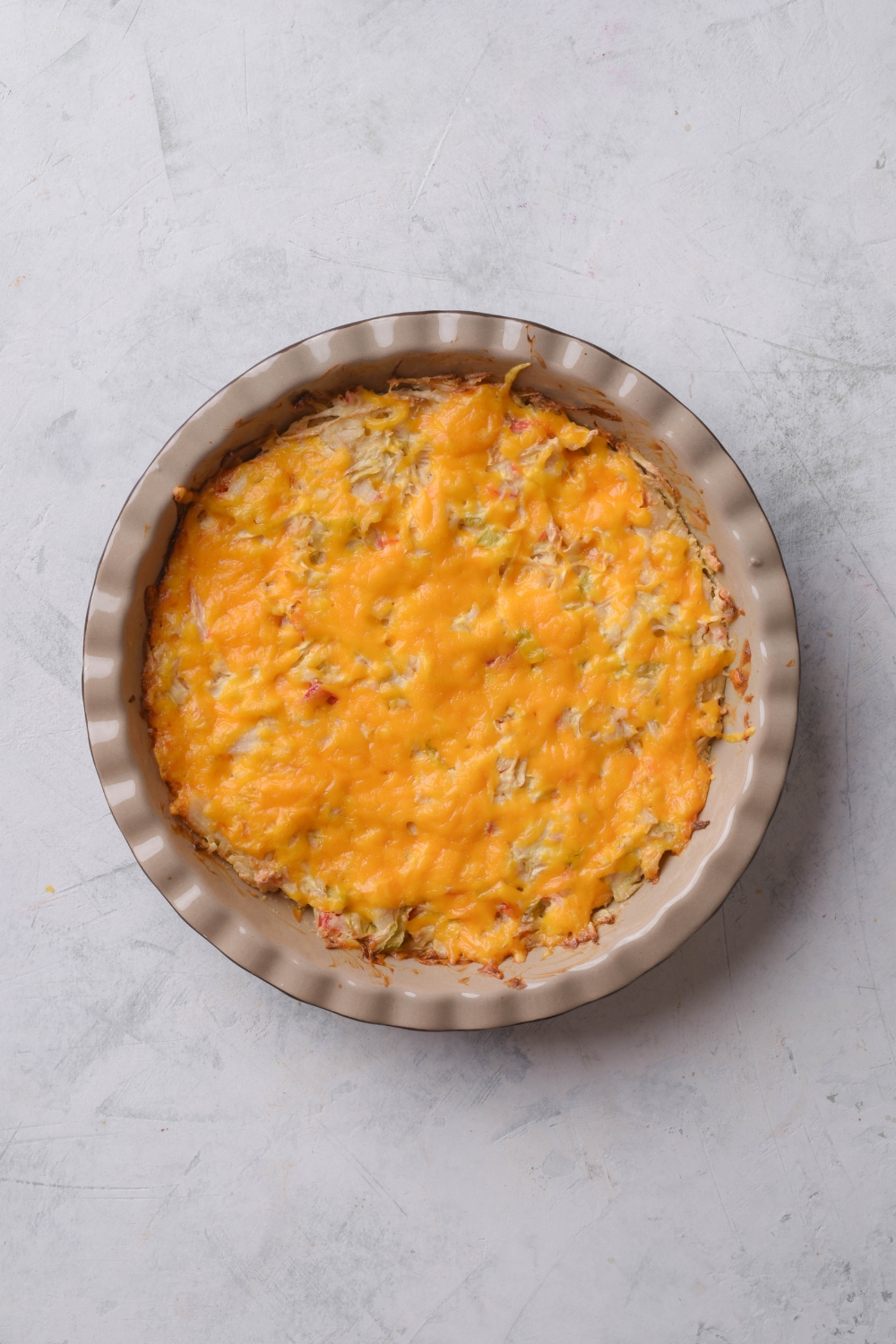 A circular baking dish filled with casserole covered in melted cheese.