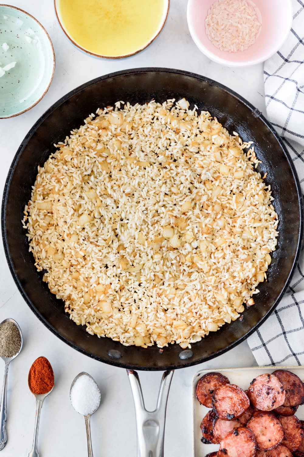 A skillet filled with diced onion and rice being browned.