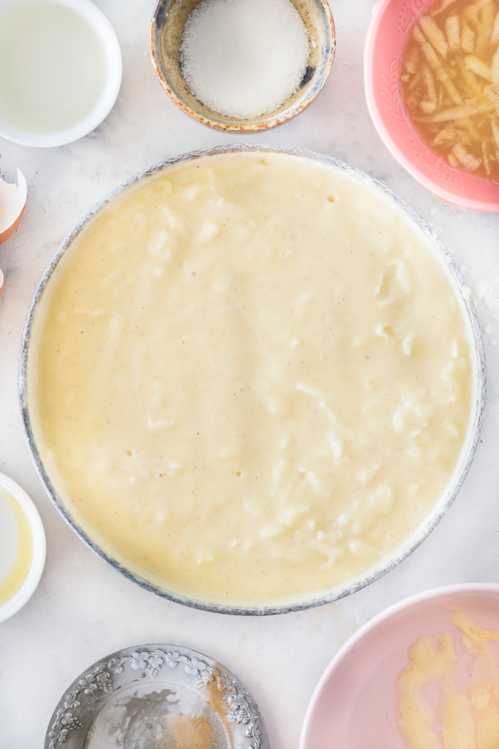 A bowl filled with chunky pancake batter surrounded by an assortment of ingredients.