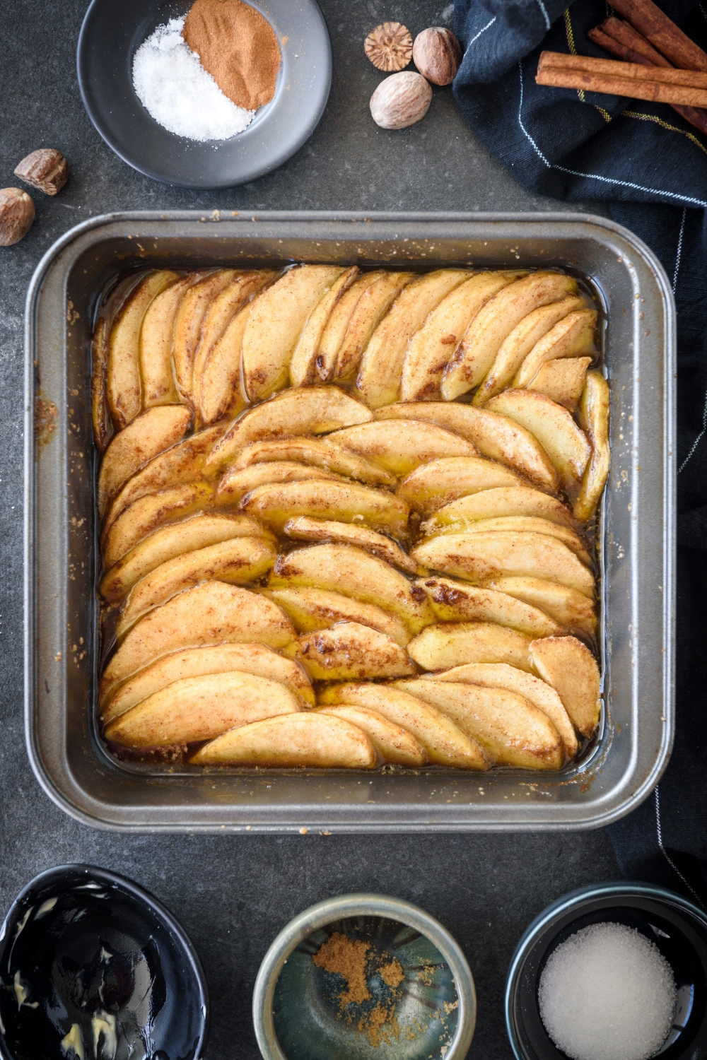 A square baking dish filled with freshly baked apple slices coated in cinnamon and sugar.