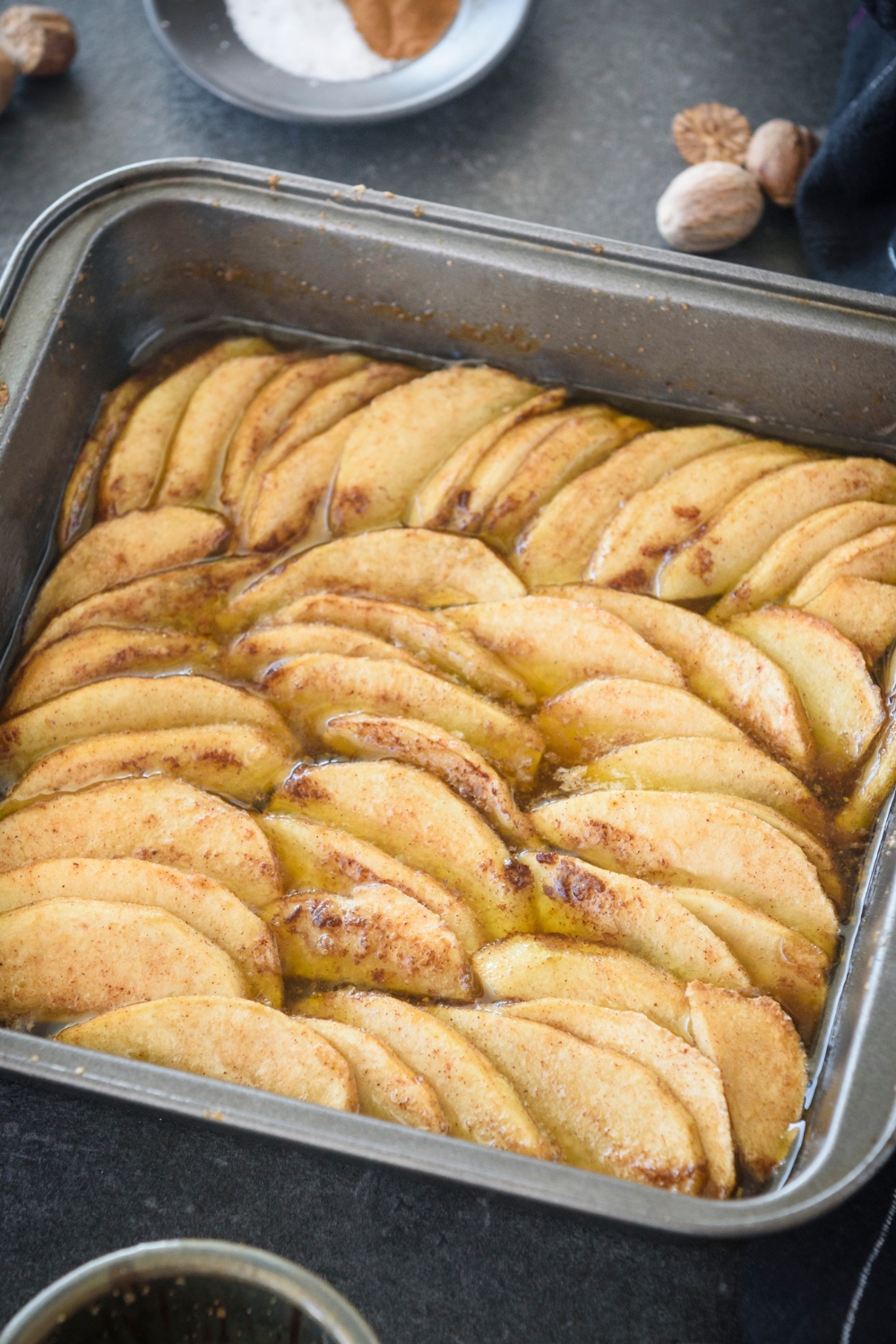 A square baking dish filled with freshly baked apple slices coated in cinnamon and sugar.