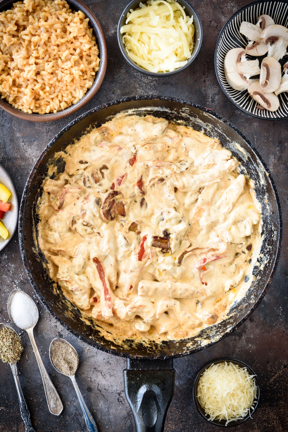 A skillet filled with chicken, peppers, and mushrooms in a seasoned cream sauce.