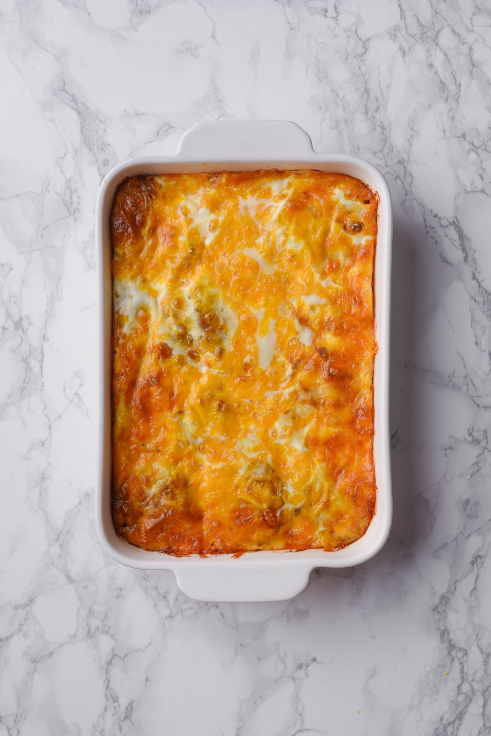 A baking dish filled with freshly baked casserole covered in melted cheese.