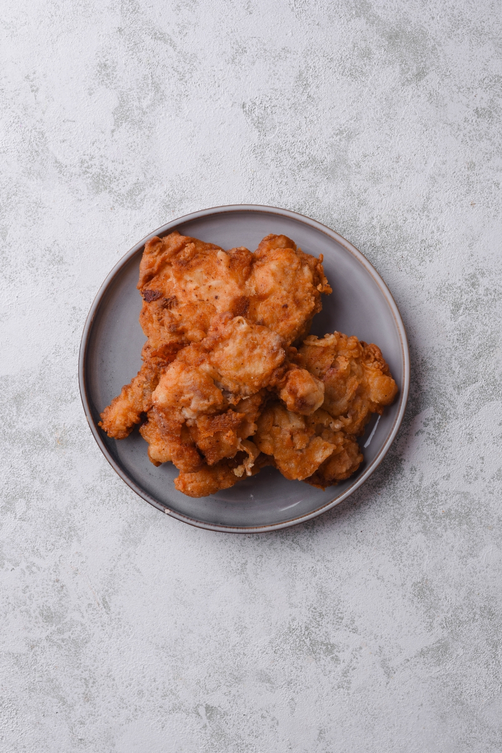 Overhead view of a plate of fried chicken piled high on top of each other.