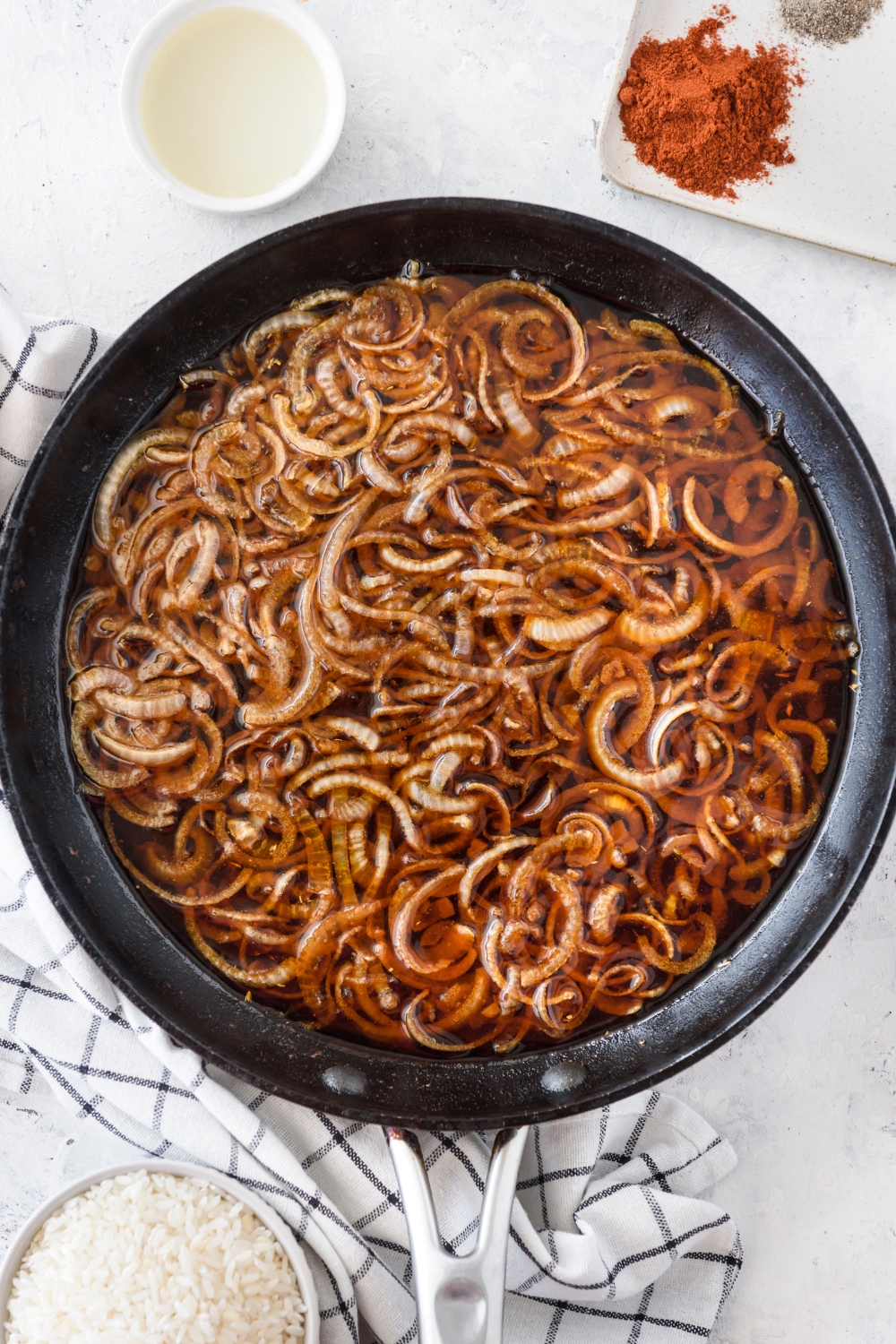 A skillet filled with sliced onions frying in the skillet.