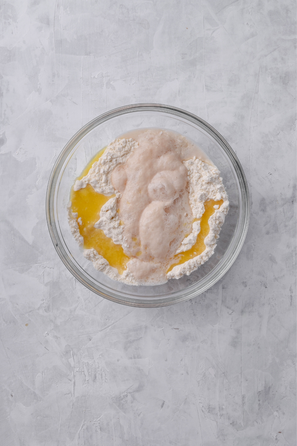 Risen yeast mixture in a bowl with flour and melted butter