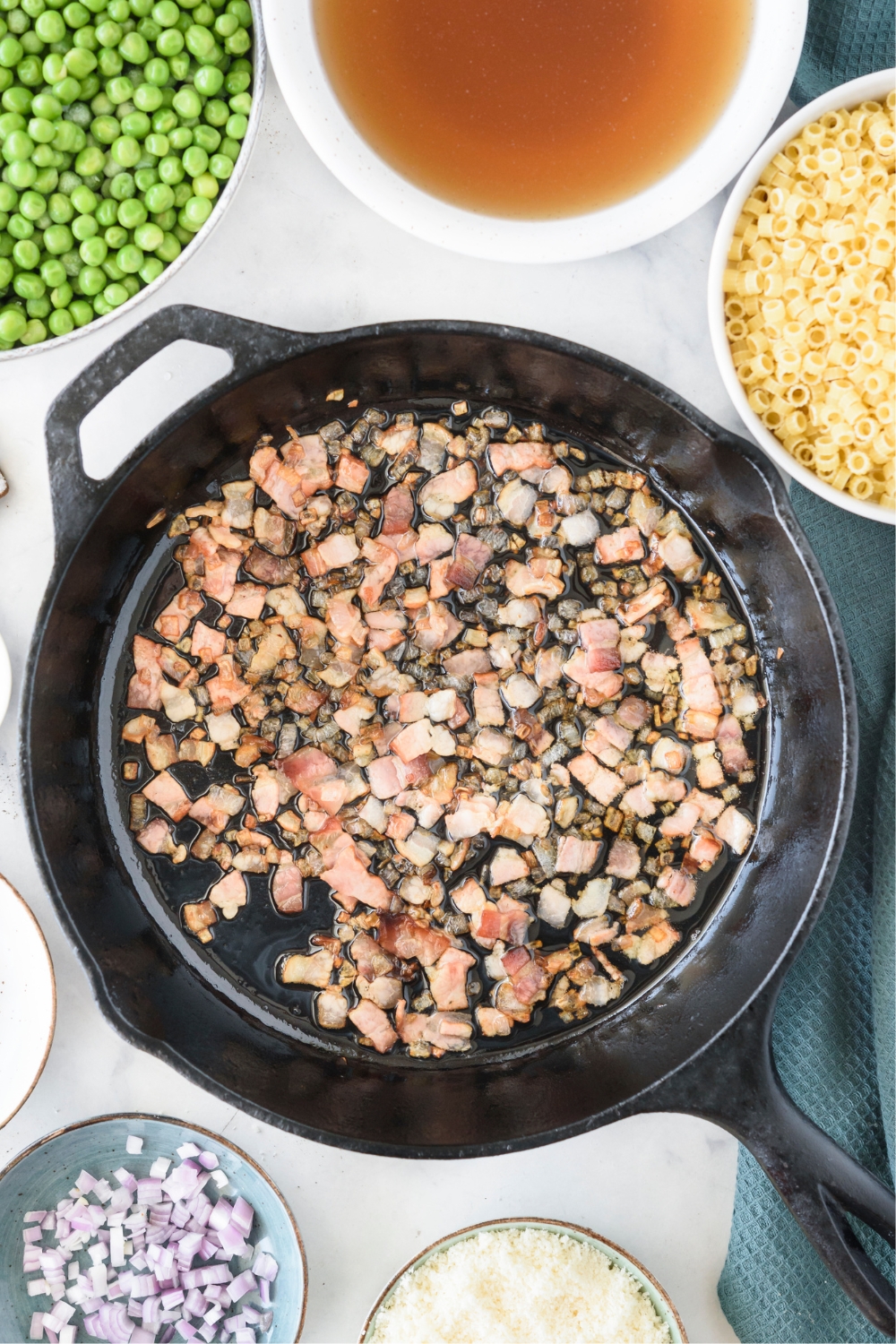 Bacon and peas sautéing in a black skillet