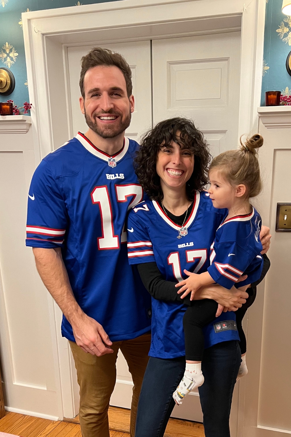 A man, woman, and little girl in a dinning room. The woman is holding the girl.