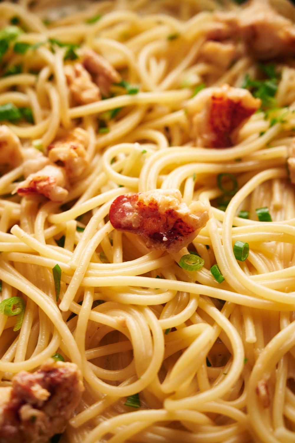 Cooked spaghetti mixed with lobster meat, green onion, and fresh herbs.