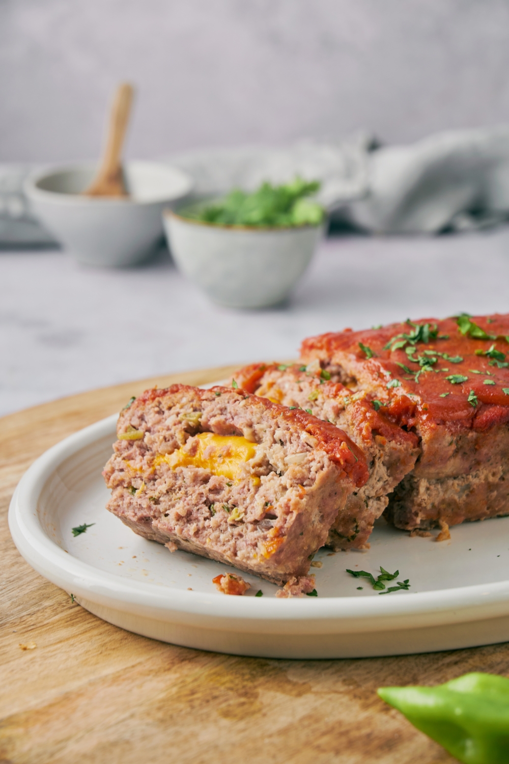 Meatloaf covered in red sauce with two slices cut and laid on top of each other. The meatloaf is filled with melted cheese.